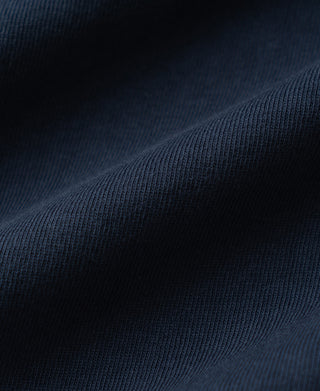 A close-up of dark navy blue ribbed fabric with soft folds and a fine knit texture.