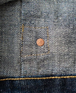 Indigo denim jacket pocket flap with copper button and bar tack stitching