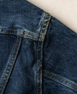 Indigo denim jacket pocket opening with vertical seam stitching and topstitching