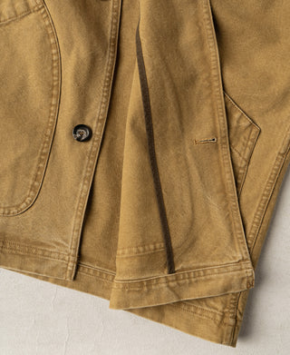 Khaki canvas field jacket detail with a button, flap pocket, stitched hem and buttonhole.