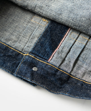 Indigo denim jacket hem panel with metal snap and orange-brown topstitching