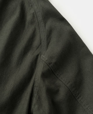 Olive canvas field jacket side panel with curved seam and stitched pocket opening