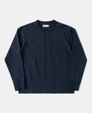 A dark navy blue long-sleeve henley shirt with a three-button placket, laid flat against a light gray background.