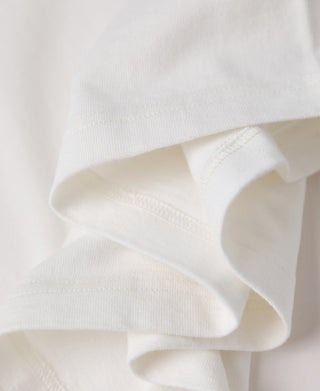 Close-up of a soft off-white or cream-colored fabric with a fine ribbed texture and folded edges.