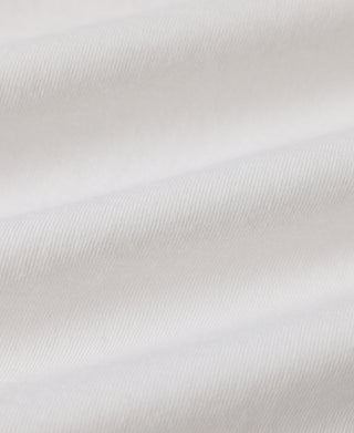 A close-up of white fabric with soft folds and a fine woven texture.