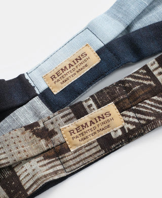 Close-up of two printed neck scarves with REMAINS labels and stitched hems