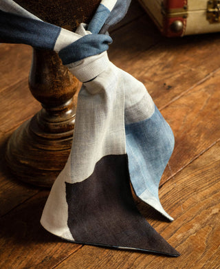 Blue and white printed neck scarf tied around a stand, with a long pointed end.