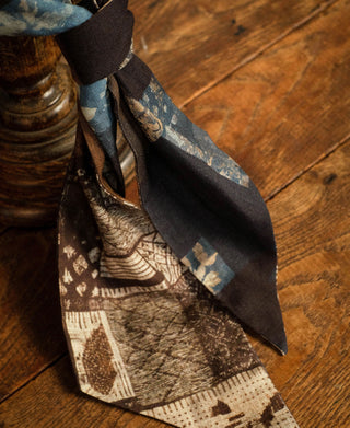 Printed neck scarf tied at the neck, showing brown geometric and blue patterned panels.