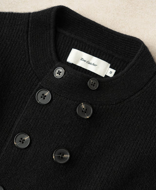 Black knit cardigan neckline close-up with white neck label and buttons
