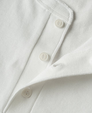 Close-up of a white knit button-up shirt showing the collar, button placket, and soft fabric texture.