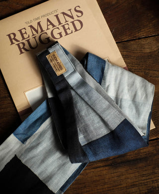 Folded blue, white, gray, and black scarf with a small woven label.