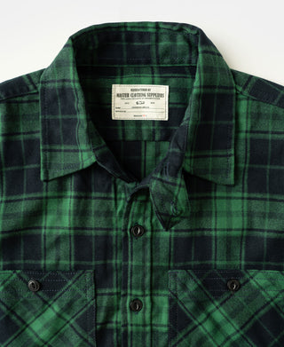 Green plaid work shirt chest with button placket, flap pockets, and logo label