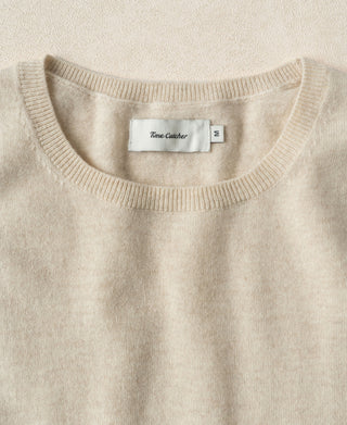 Apricot crewneck sweater neckline with ribbed trim and centered label.