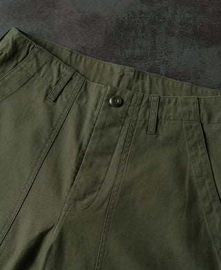 Olive fatigue pants waistband detail with belt loops, front button, and pleated front.