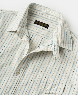 Angled close-up of open collar and chest pocket on the striped work shirt