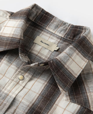 Plaid Western shirt close-up of collar and button tab on shoulder with dark and beige tones.