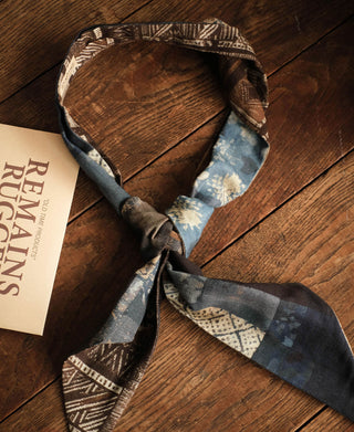 Neck scarf tied in a loop, displaying brown geometric and blue patterned panels.