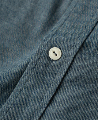 Close-up of blue flannel shirt placket with white buttons and stand collar.
