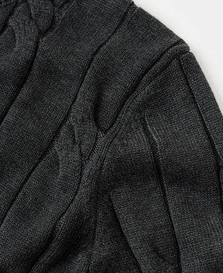 Dark gray cable-knit sweater sleeve detail with textured stitch pattern