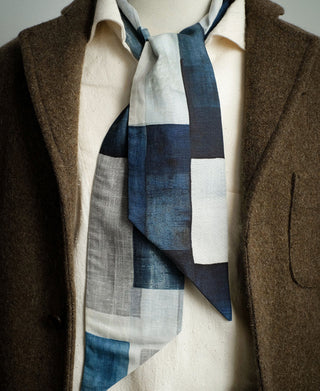 Blue and white block-print neck scarf worn over a collared shirt.