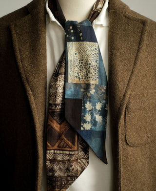 Printed neck scarf worn over a shirt, with brown, cream, and blue patchwork panels.
