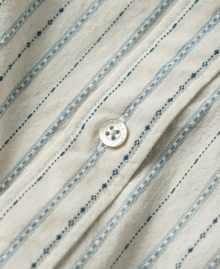 Close-up of a white shirt button and textured blue stripe pattern