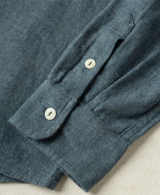 Close-up of blue flannel sleeve cuff with white button and stitched placket.