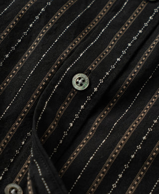 Close-up of a dark button on the shirt's black jacquard stripe fabric
