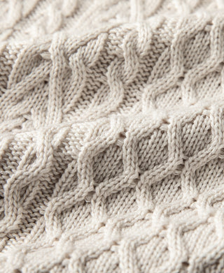 Close-up of cream cable knit pattern with raised braided stitches