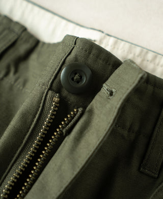 Close-up of olive front closure area with zipper, button, and pocket flap