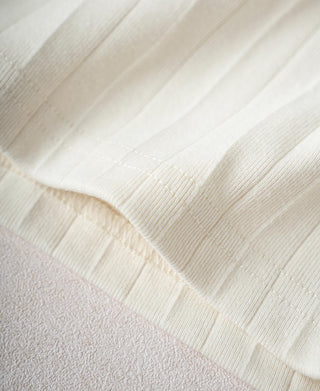 Close-up of ribbed cotton hem and stitching on the oatmeal white T-shirt
