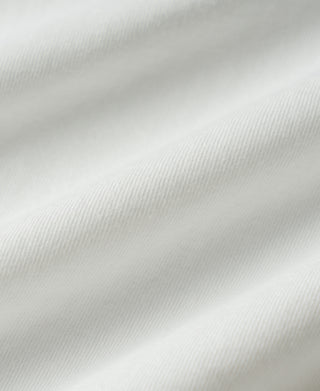 A close-up of white fabric with soft diagonal folds and visible woven texture.