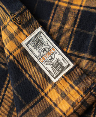 Yellow and navy plaid work shirt with white care label on chest