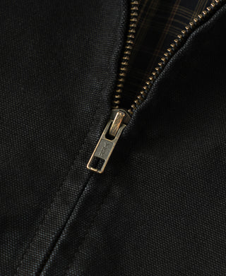 Black jacket zipper detail with brass-toned pull and metal track