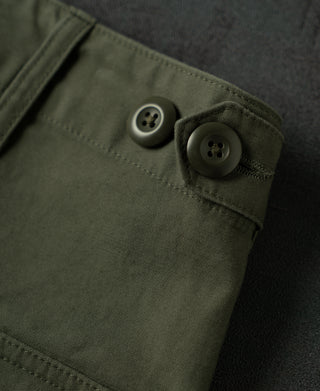 Olive fatigue pants side pocket detail with flap and two metal-look buttons.