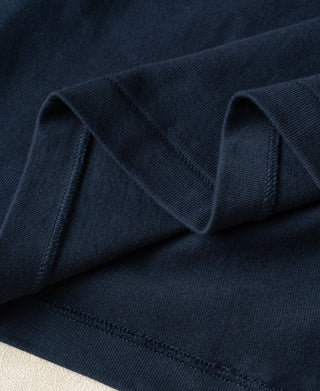 Close-up of dark navy blue knit fabric with folded edges and visible stitching.