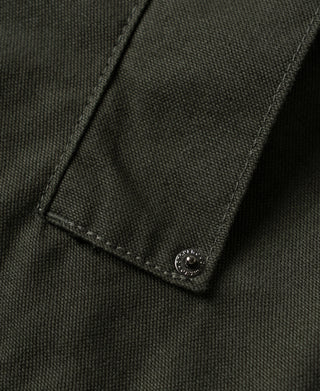 Close-up of olive canvas jacket buttoned pocket flap and textured fabric