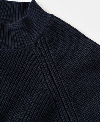 Close-up view of the stand collar, shoulder seam, and textured rib knit construction on a dark blue wool-blend cardigan sweater.