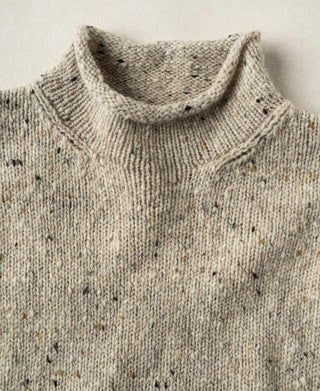 Close-up view of the ribbed roll neck collar on an ecru pure wool fisherman sweater.