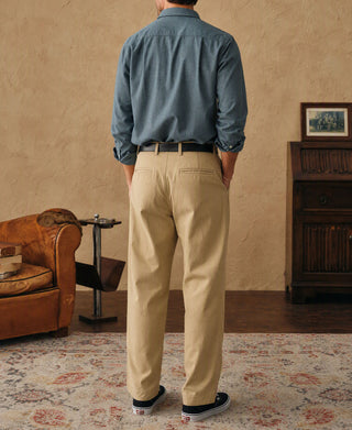 Blue flannel work shirt worn with beige trousers and sneakers; long sleeves and button front.